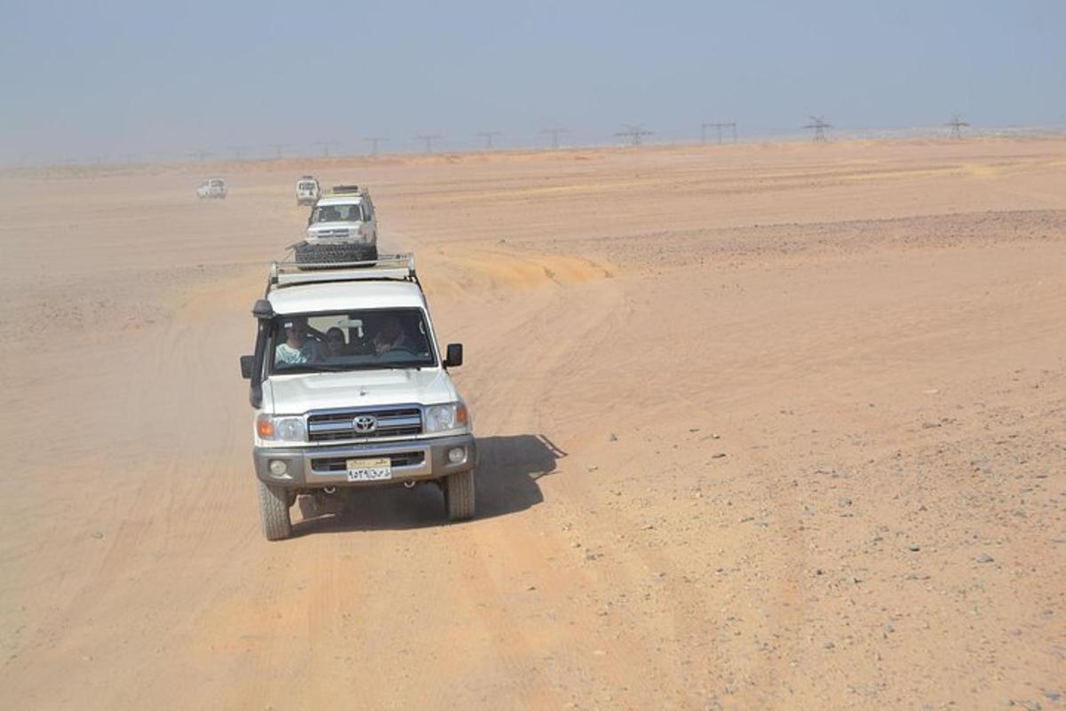 un camion che guida nel deserto con due auto sul tetto