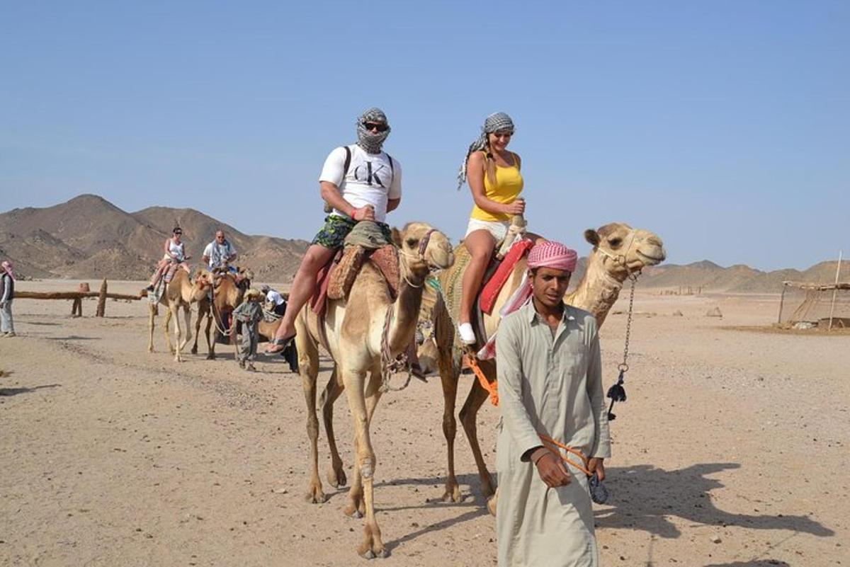 un gruppo di persone a cavallo di cammelli nel deserto