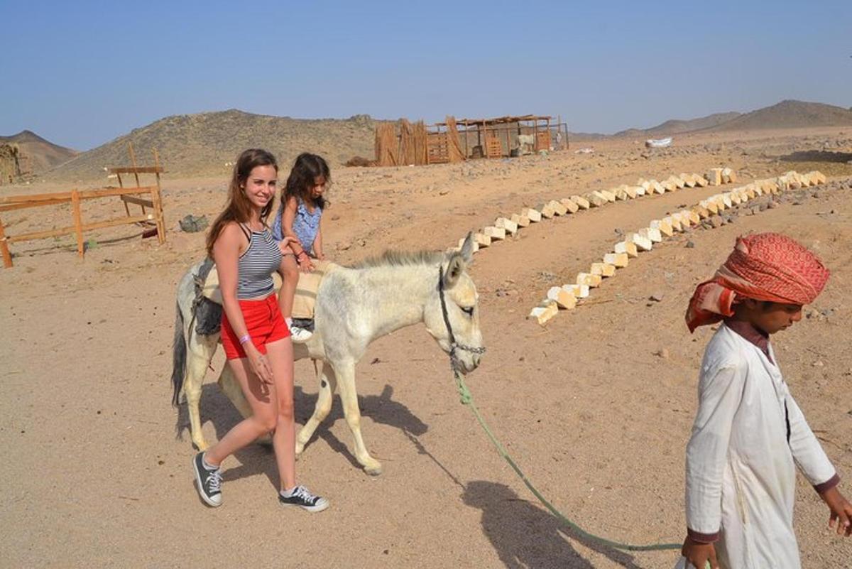 due ragazze stanno portando a spasso un asino nel deserto
