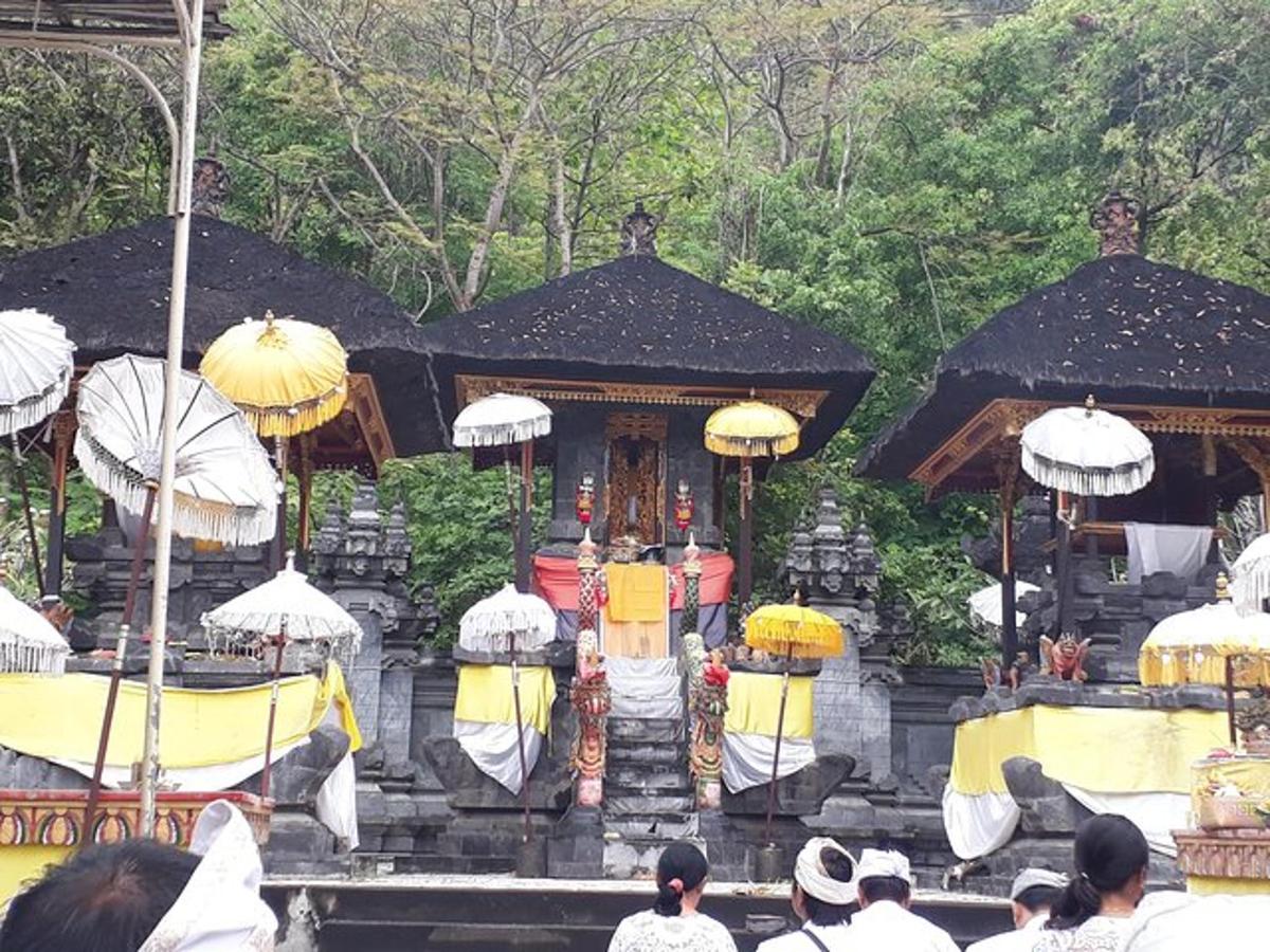 một nhóm người đứng xung quanh một ngôi đền với những chiếc ô