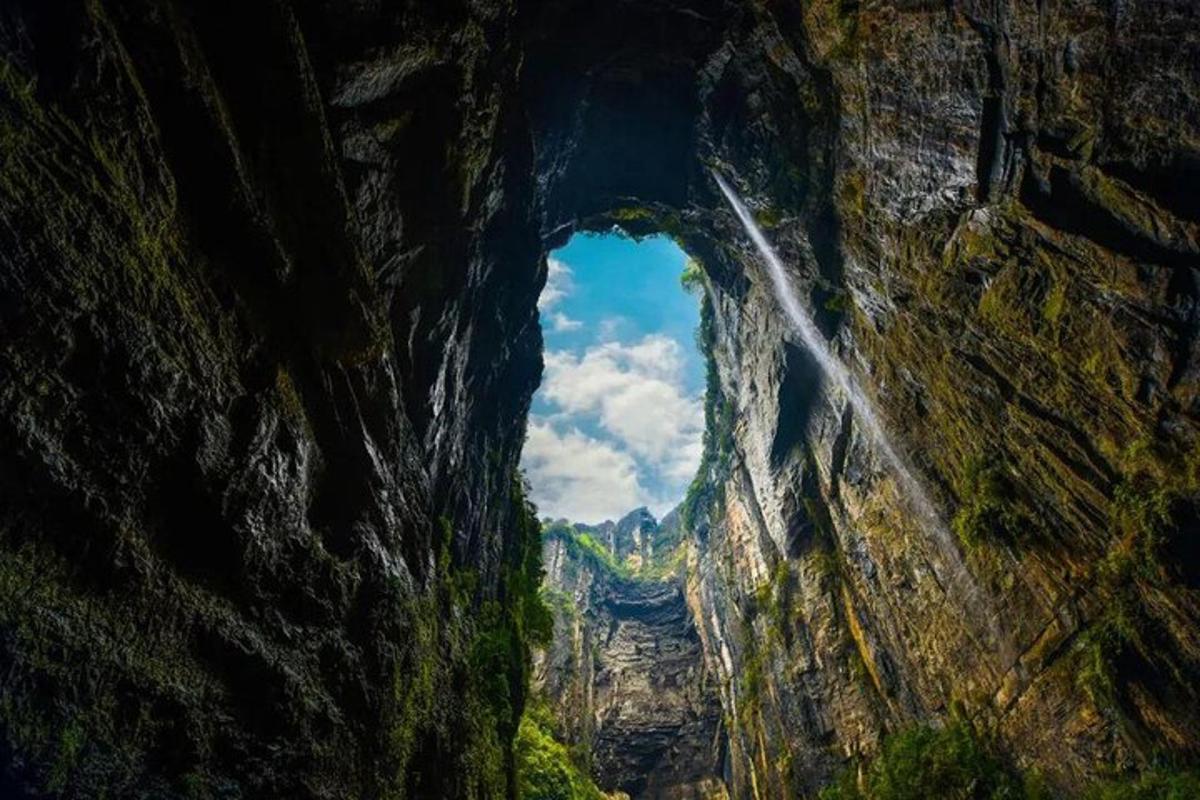 a cave with a waterfall in the middle of a canyon