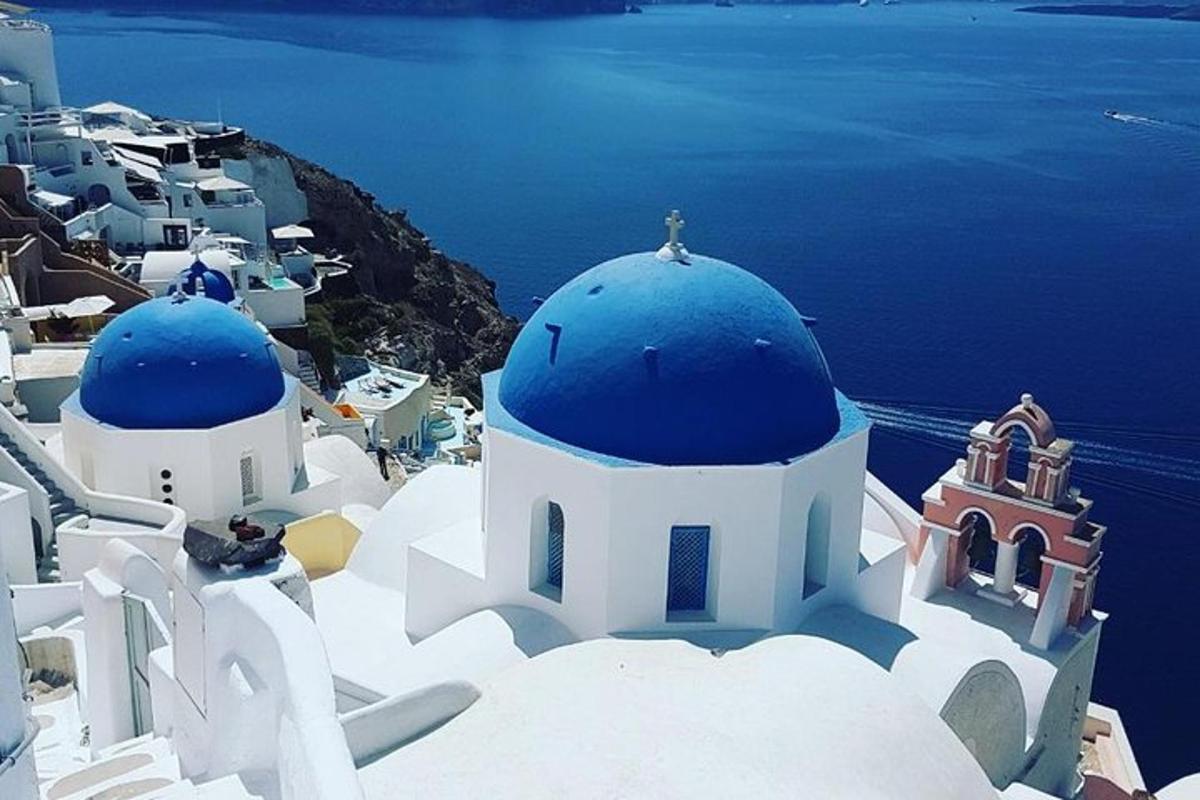 un grup d'edificis blancs amb cúpules blaves i l'oceà