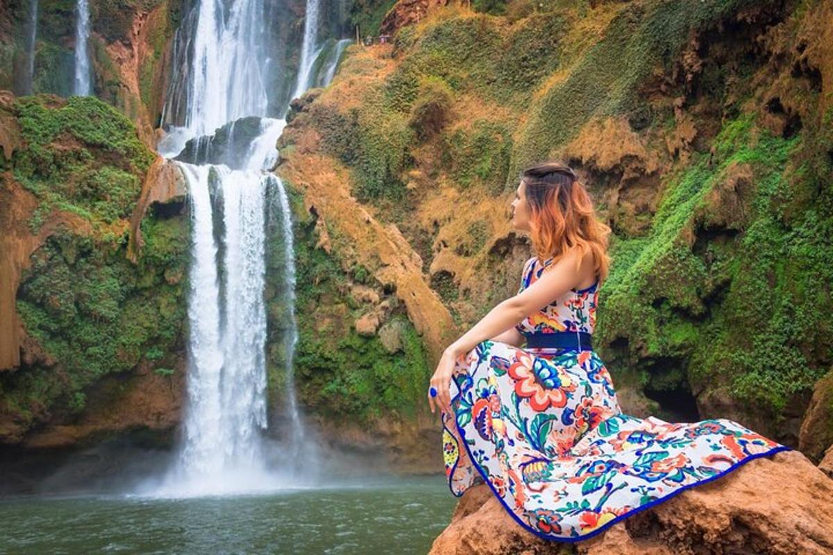 a woman sitting on a rock in front of a waterfall