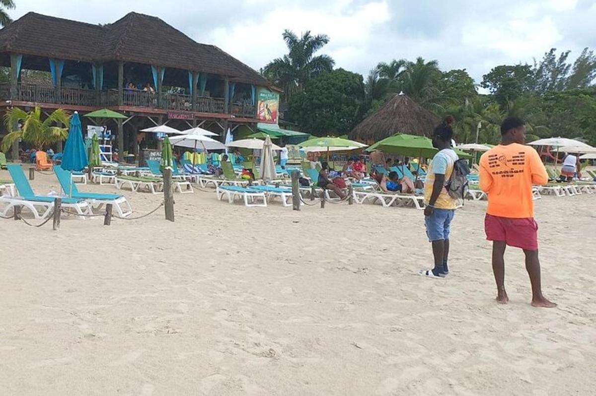 Dos personas de pie en la playa frente a un resort.
