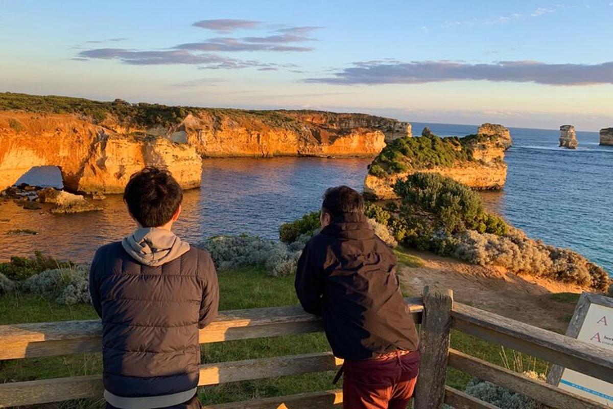 dva lidé sedící na lavičce a dívající se na oceán