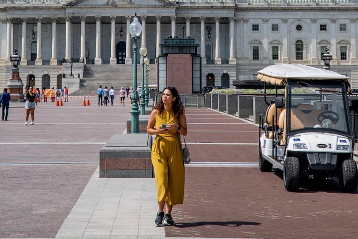 a woman in a yellow dress standing next to a golf cart