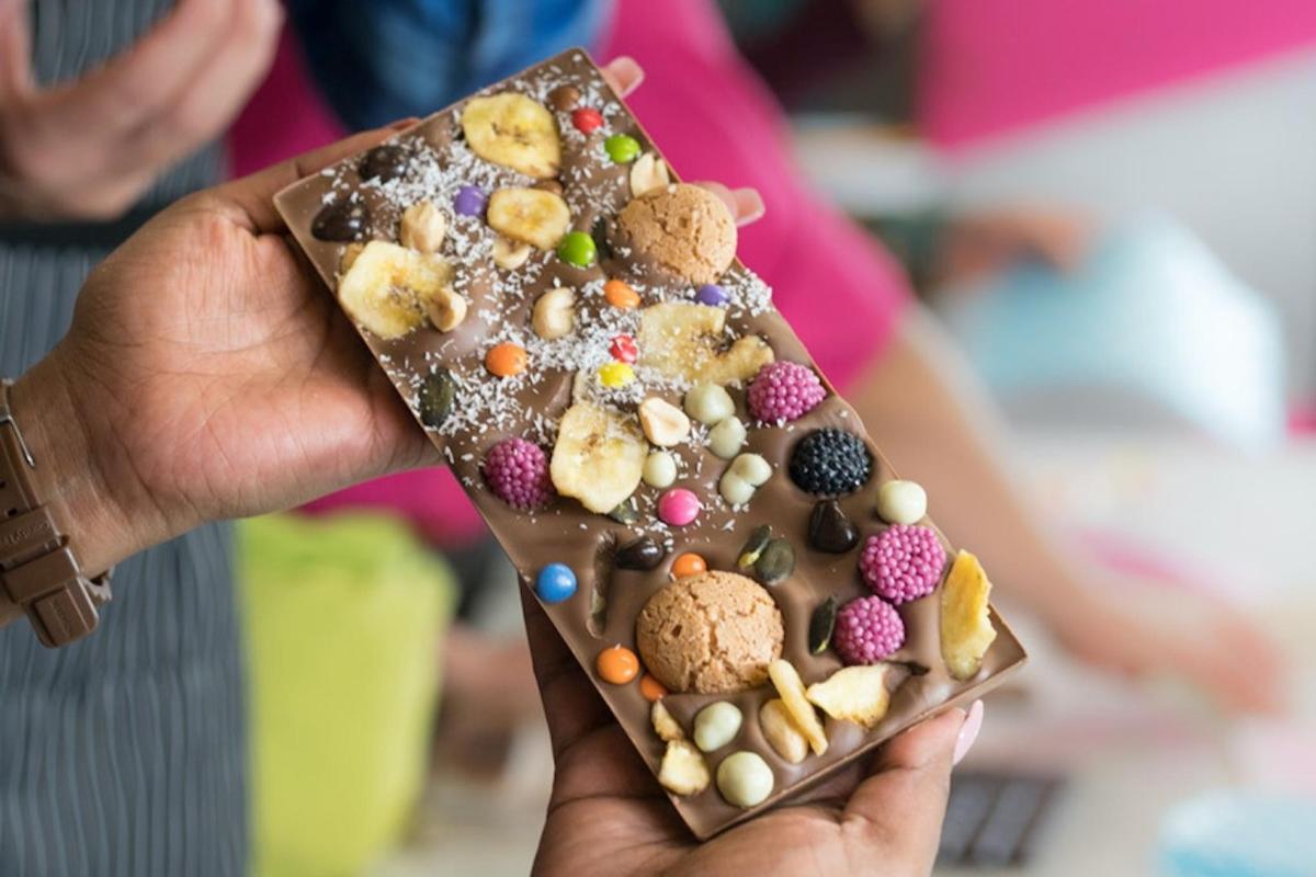 una persona che tiene in mano una barretta di cioccolato piena di biscotti e marshmallow