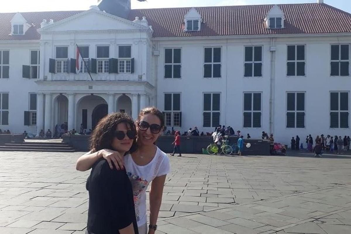 two women standing in front of a white building