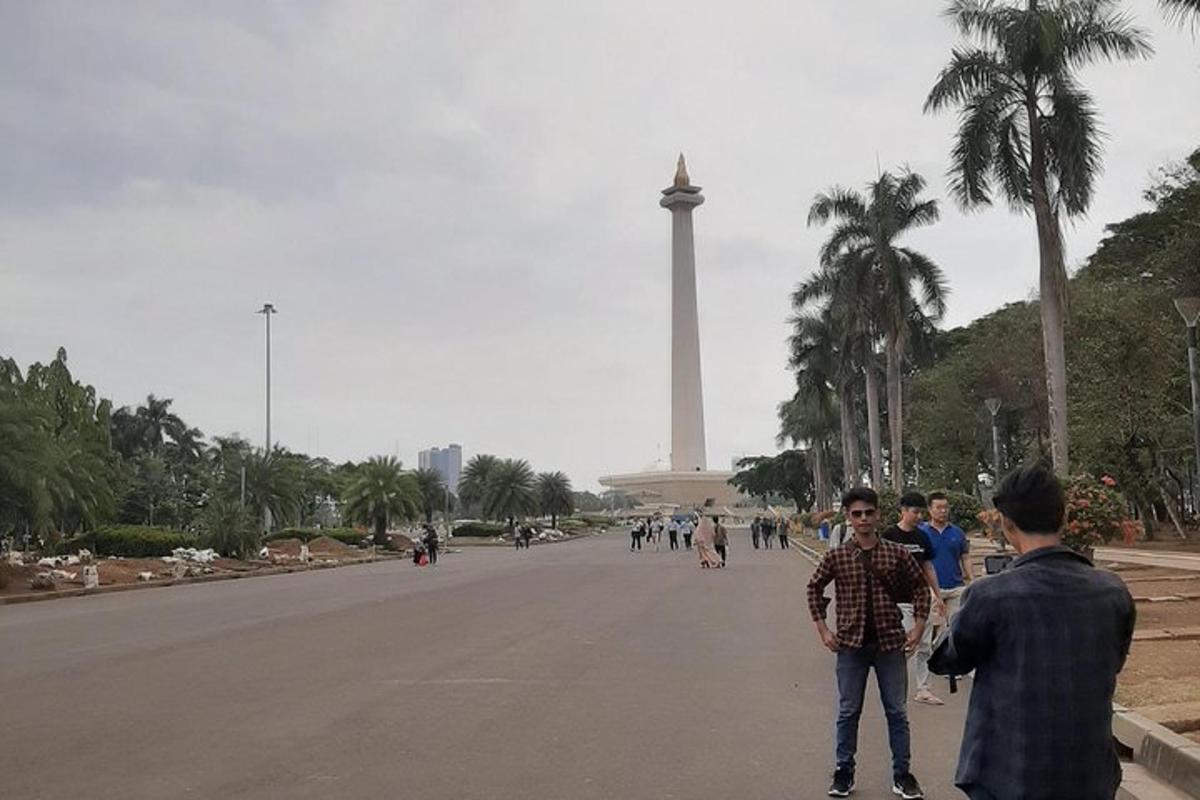 a group of people walking down a street in front of a monument