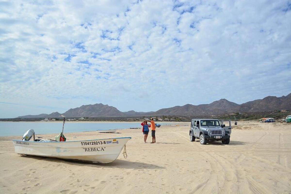 um jipe estacionado na praia ao lado de um barco