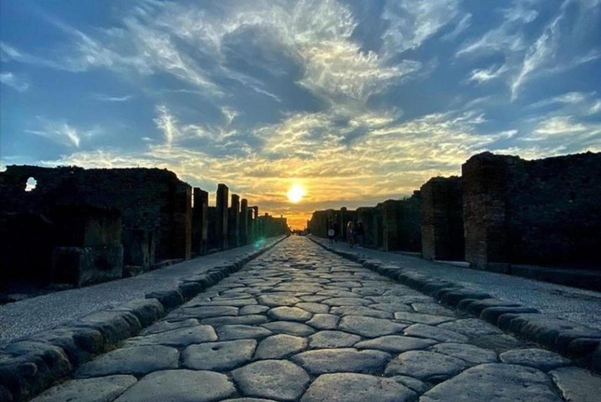 una strada acciottolata con il tramonto sullo sfondo