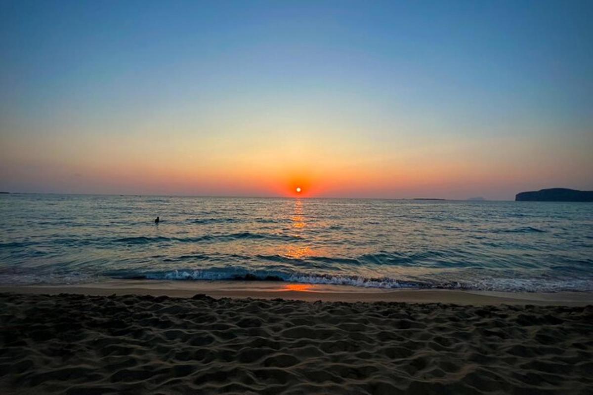 una posta de sol a la platja amb una persona a l'aigua