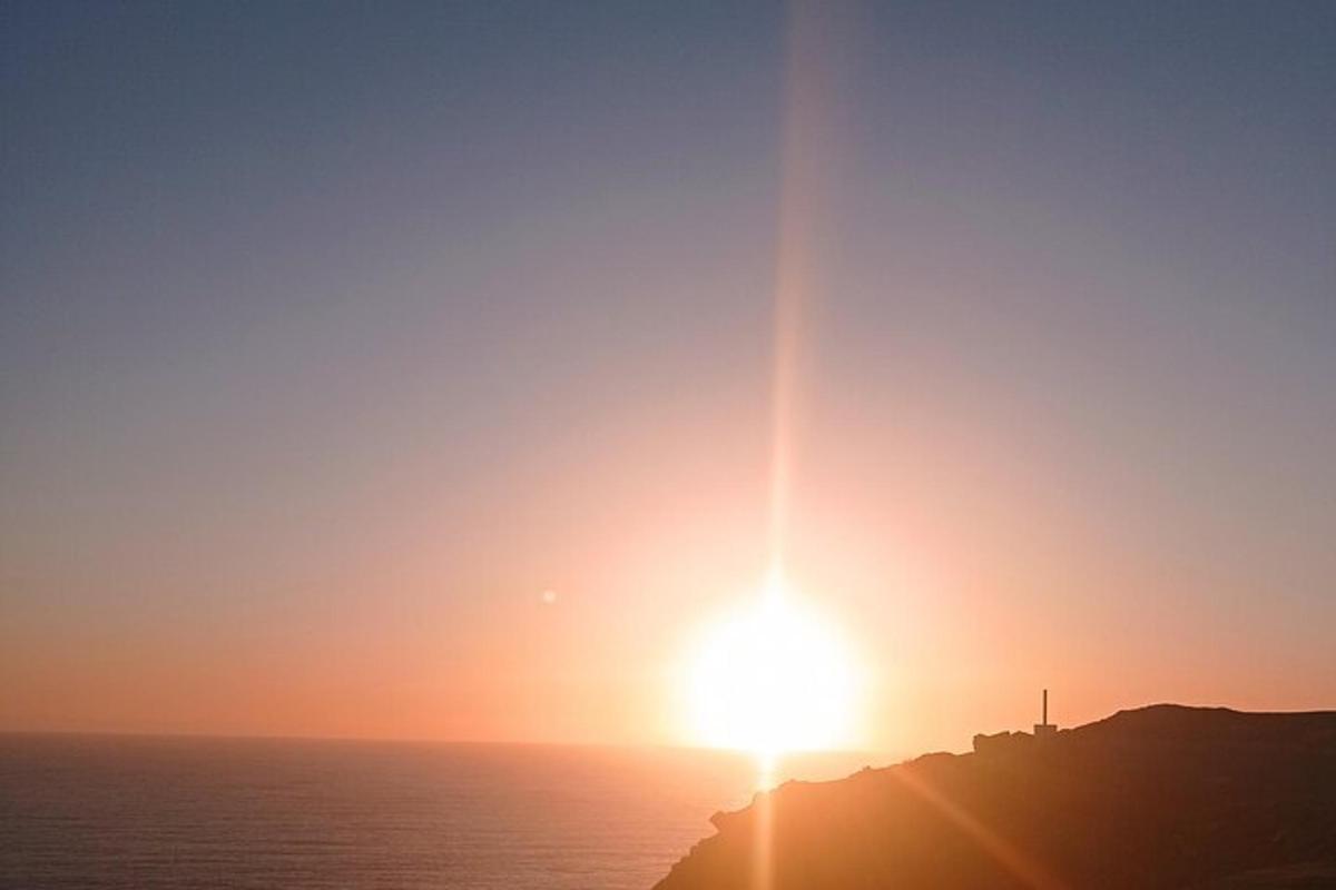 ein Sonnenuntergang über dem Meer mit der Sonne, die auf einem Berg untergeht