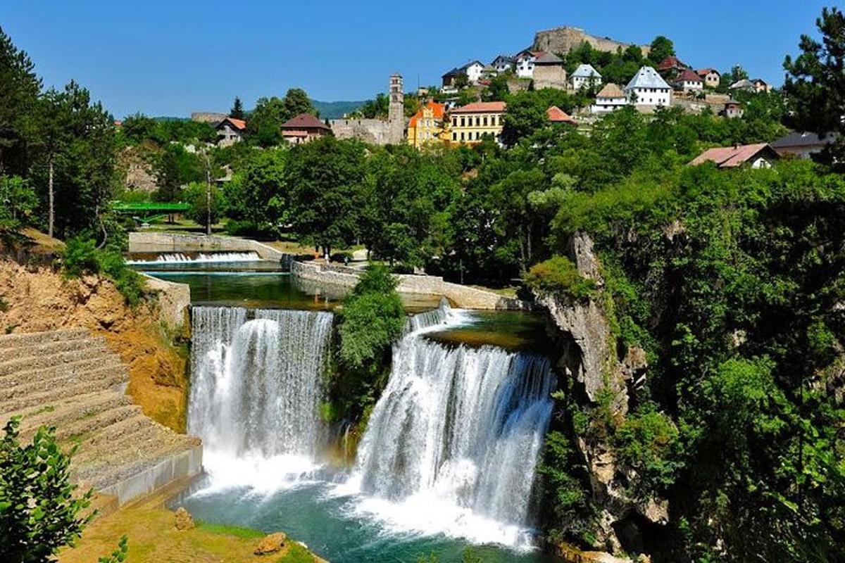 a waterfall in a river with a city in the background