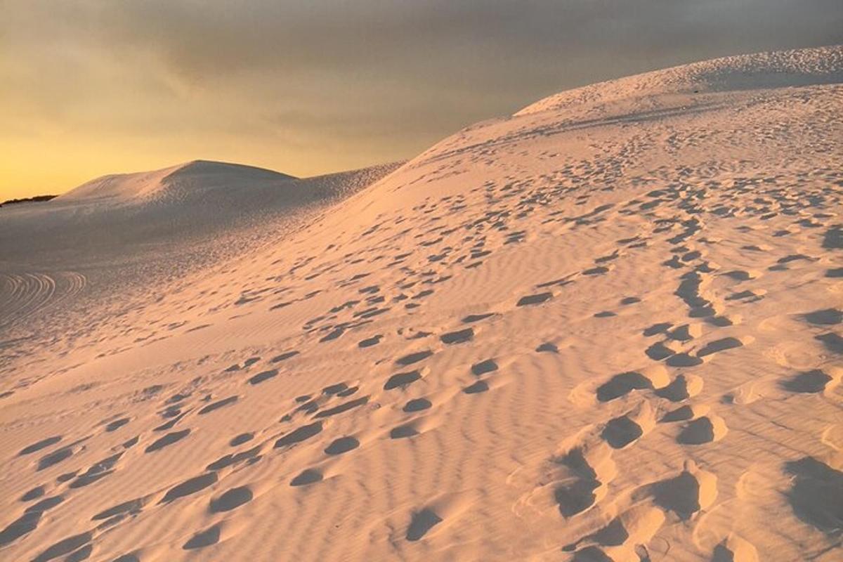 una duna di sabbia con impronte al tramonto