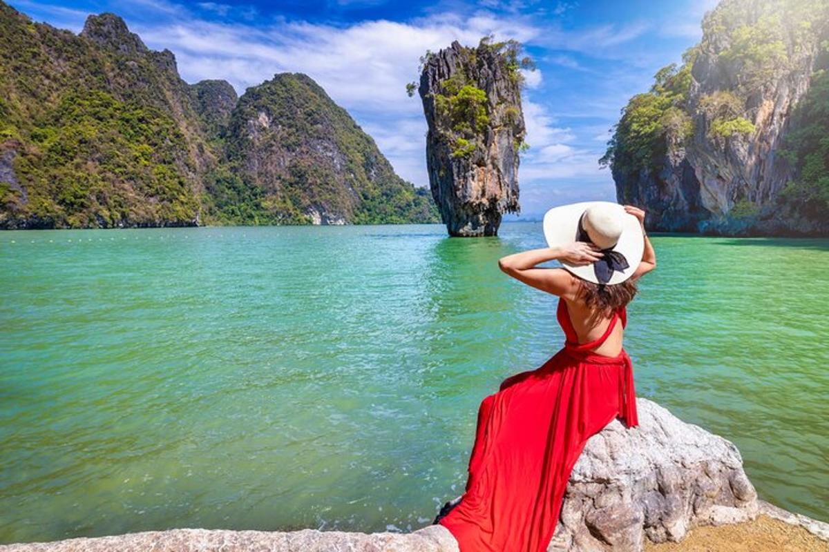 a woman in a red dress standing on a rock in the water