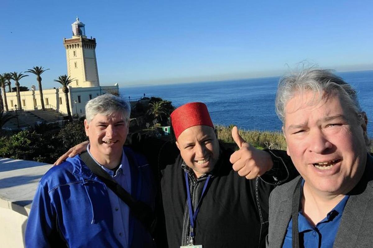 Un grupo de tres hombres de pie frente a un faro.