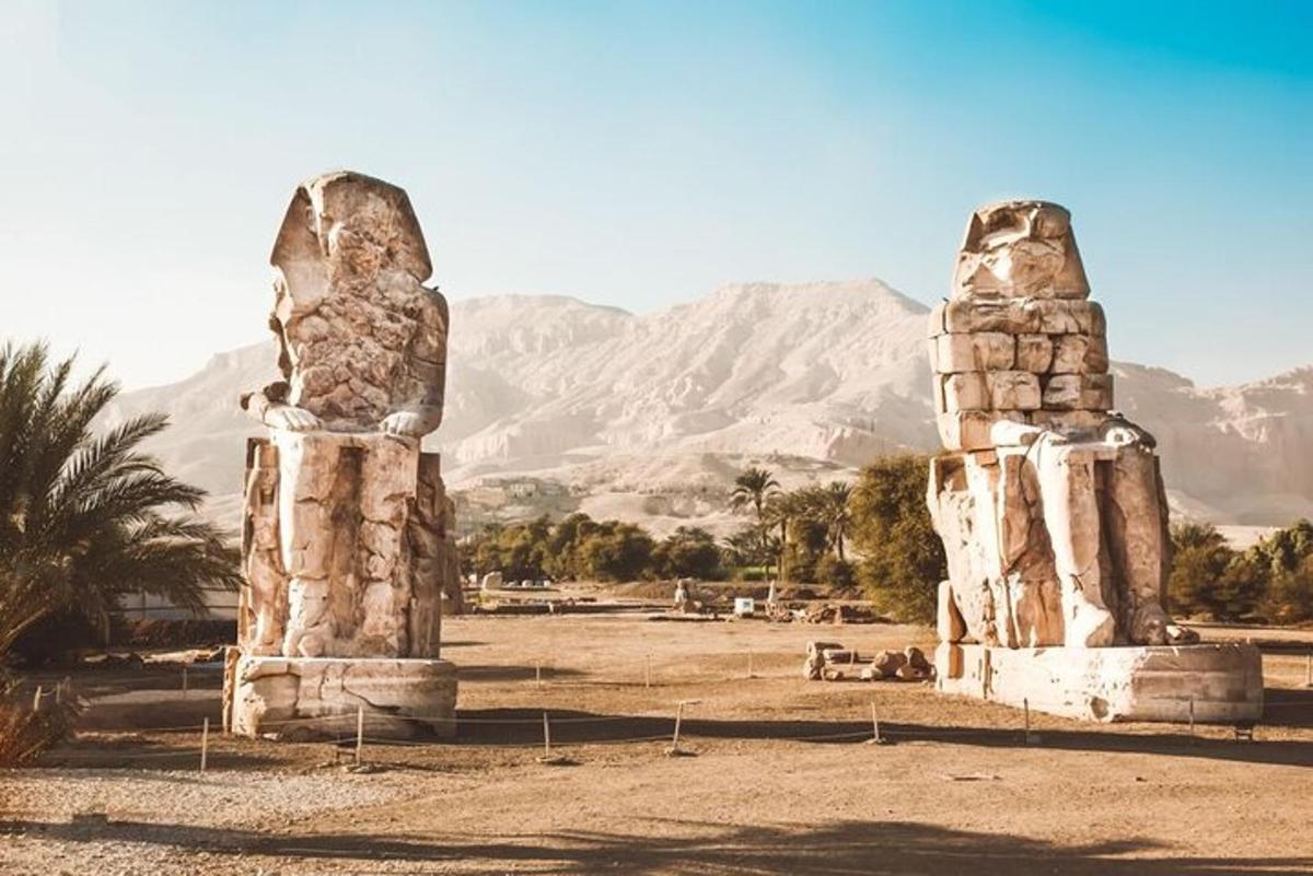 две каменни статуи в пустинята с планини на заден план