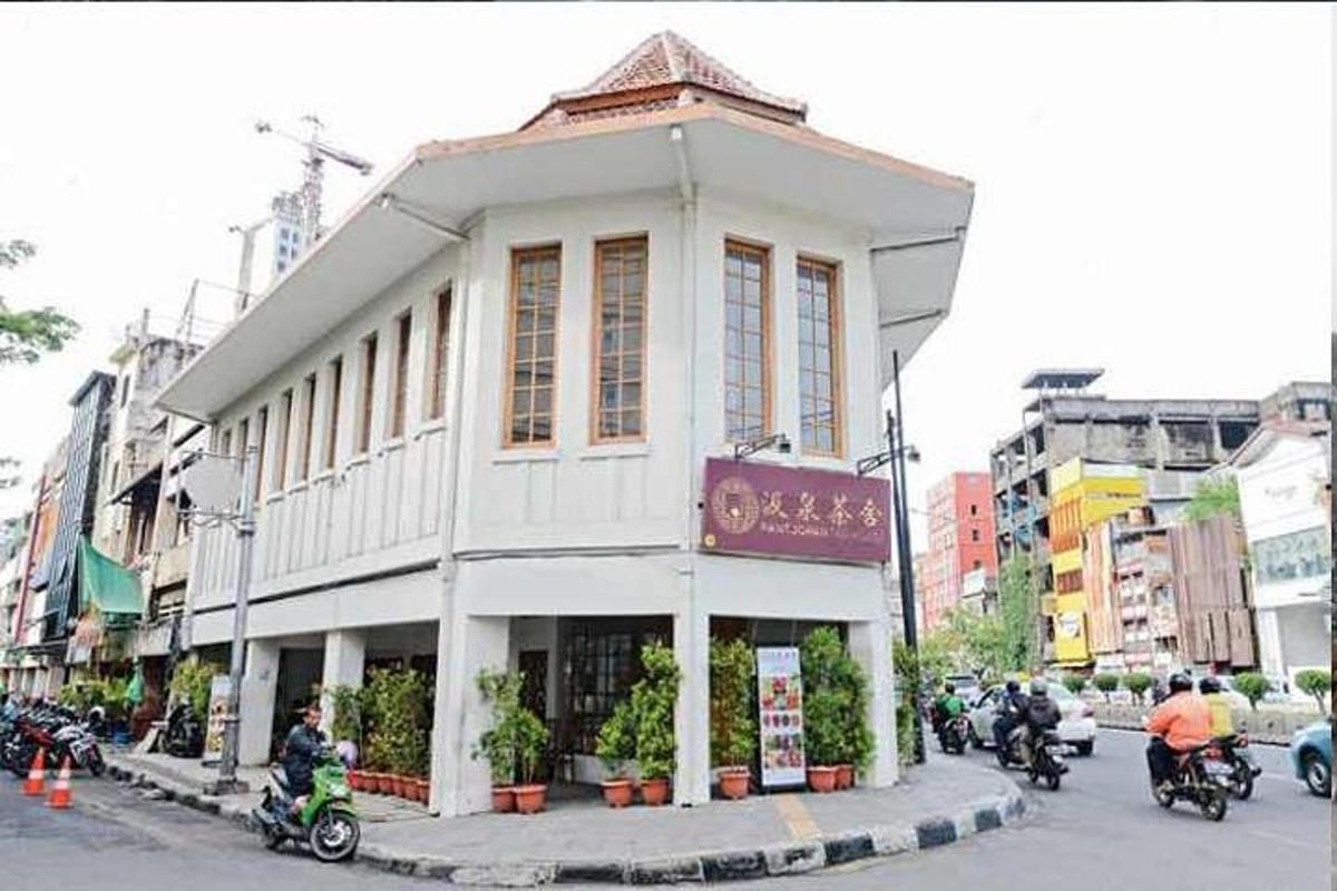 sebuah bangunan putih di jalan bandar dengan orang bermotosikal