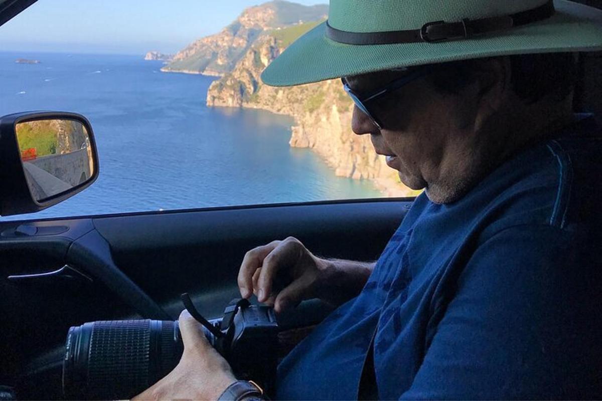 seorang lelaki bertopi duduk di dalam kereta sambil melihat telefon bimbitnya