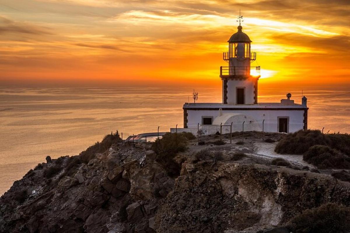 un faro su una scogliera con il tramonto sullo sfondo