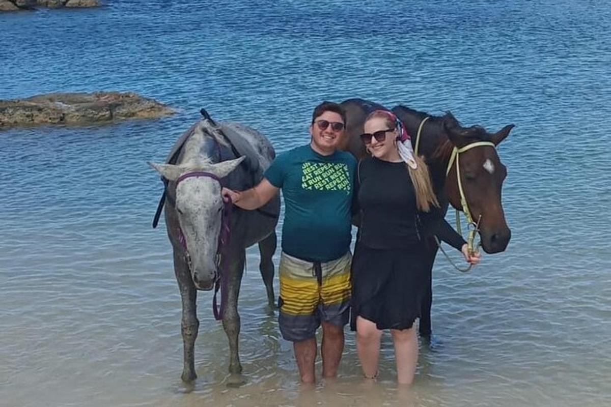 un uomo e una donna in piedi nell'acqua con un cavallo