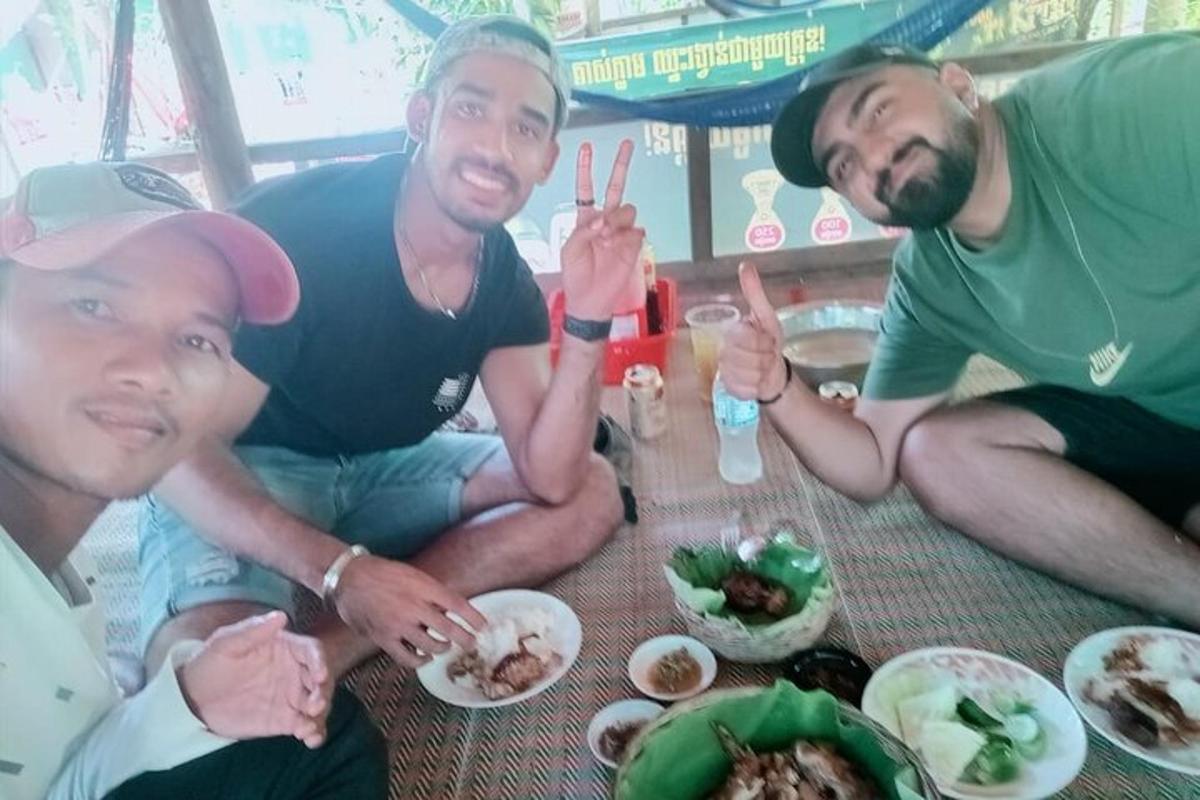 três homens sentados ao redor de uma mesa com pratos de comida