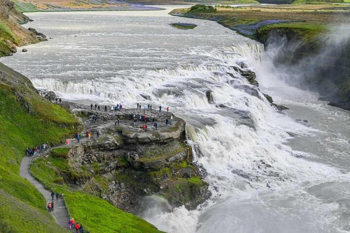 un gruppo di persone in piedi sul bordo di una cascata