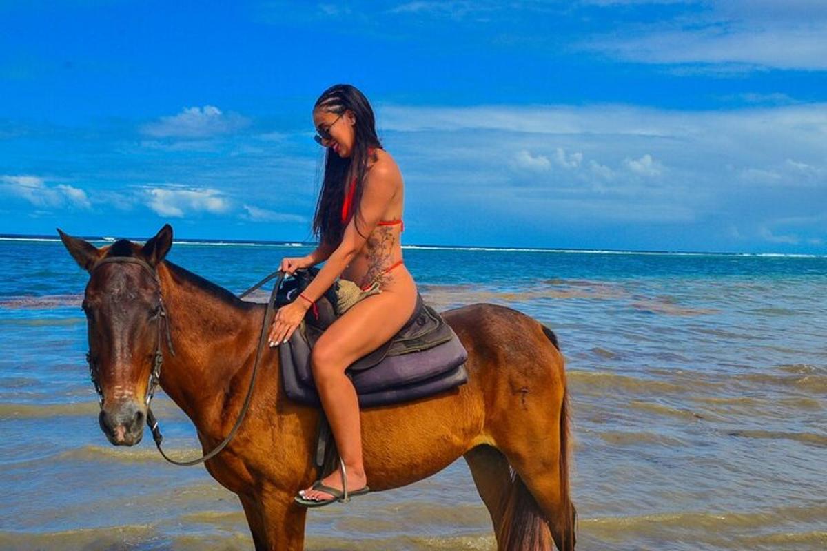 una donna in bikini a cavallo sulla spiaggia