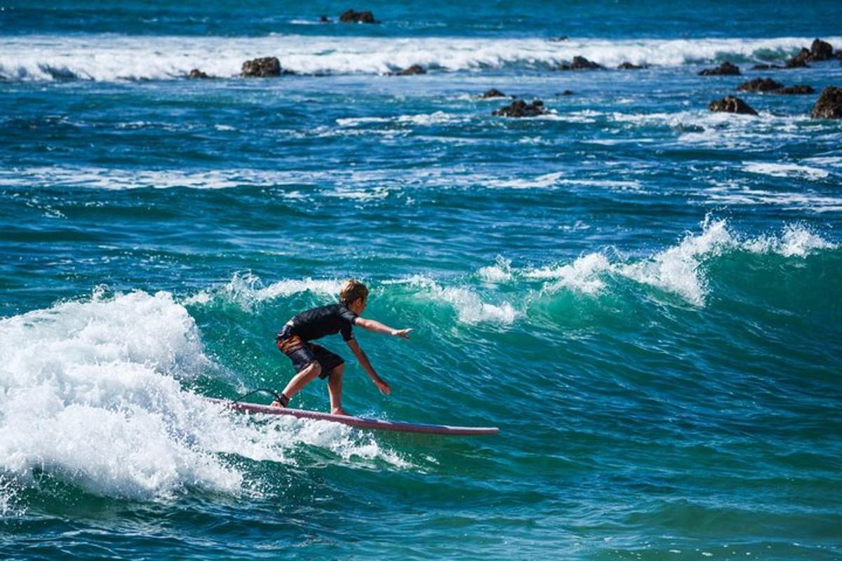 un noi jove cavalcant una onada sobre una taula de surf a l'oceà