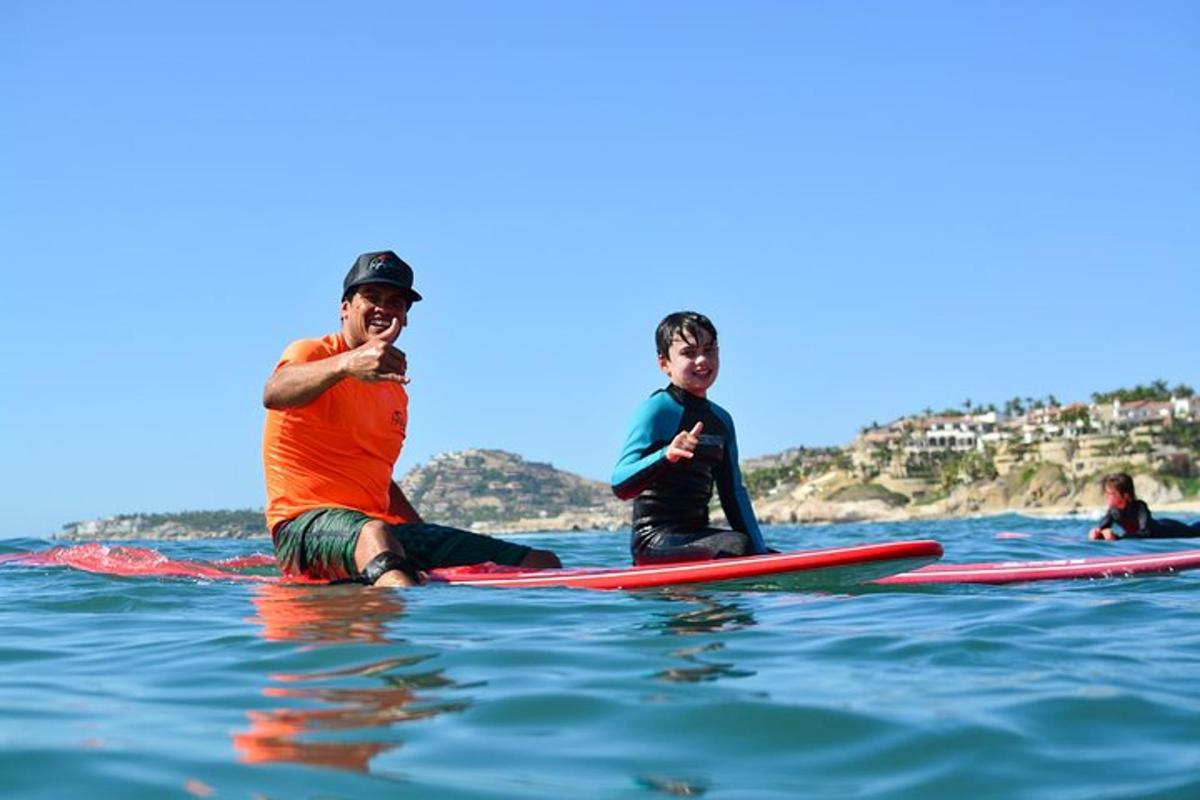 un home i un nen asseguts sobre taules de surf a l'aigua