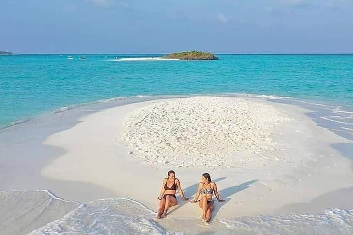 hai người phụ nữ mặc bikini đang đi bộ trên bãi biển