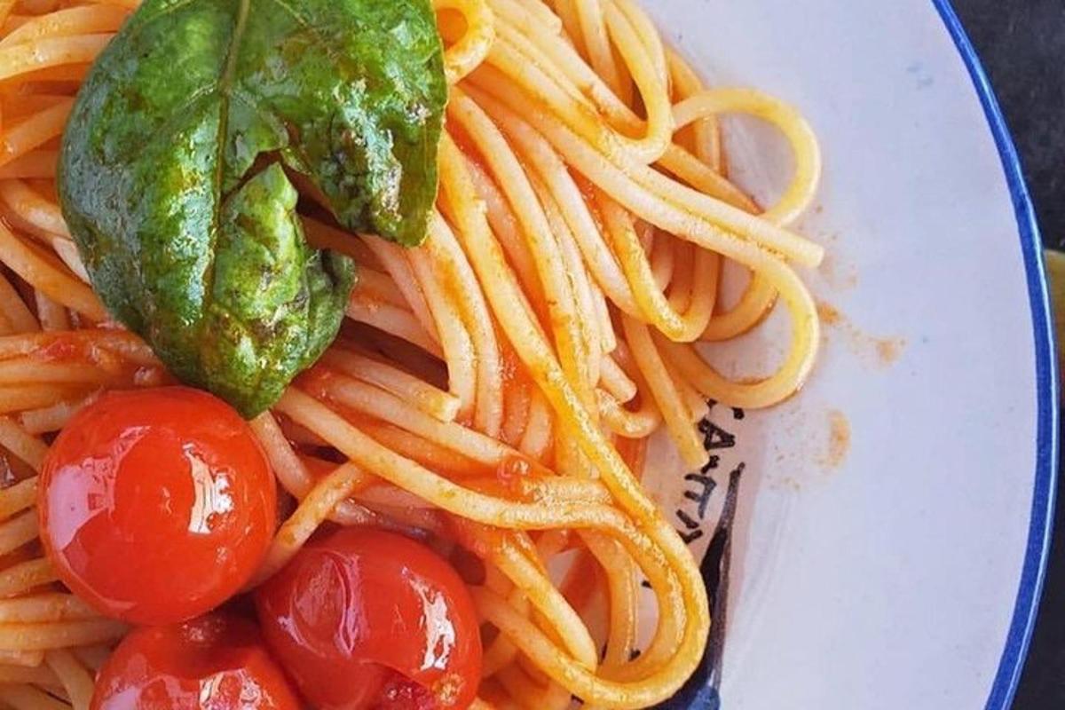um prato de macarrão com tomate e picles