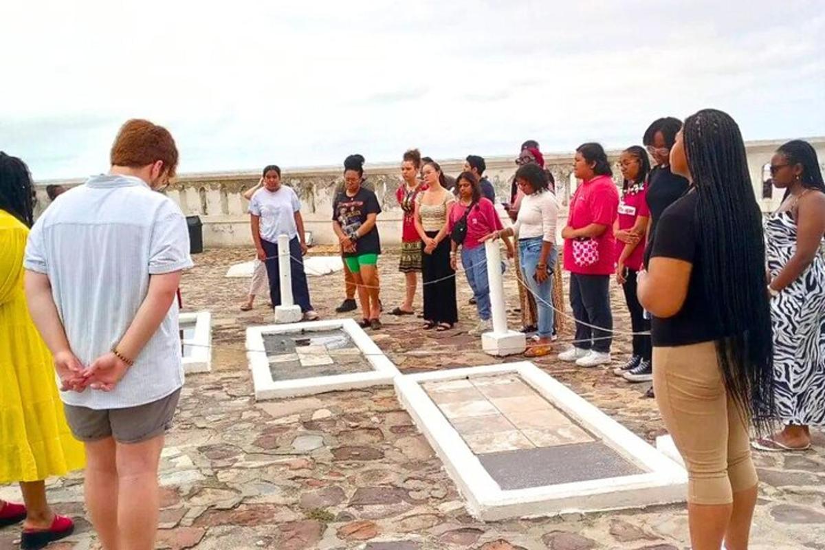 Un grupo de personas de pie alrededor de un hombre mirando artefactos.