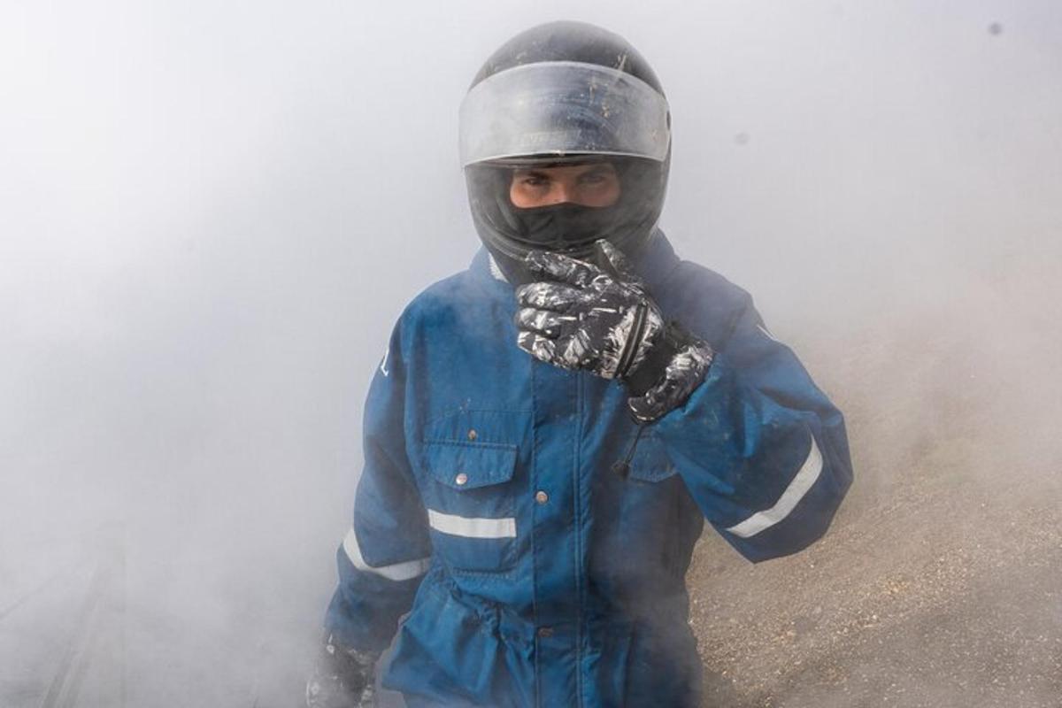 muž s prilbou a maskou stojaci v dyme