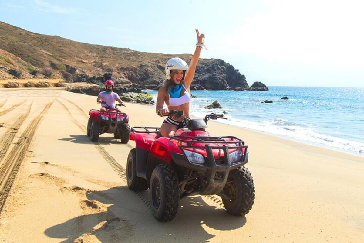due persone stanno guidando dei quad sulla spiaggia