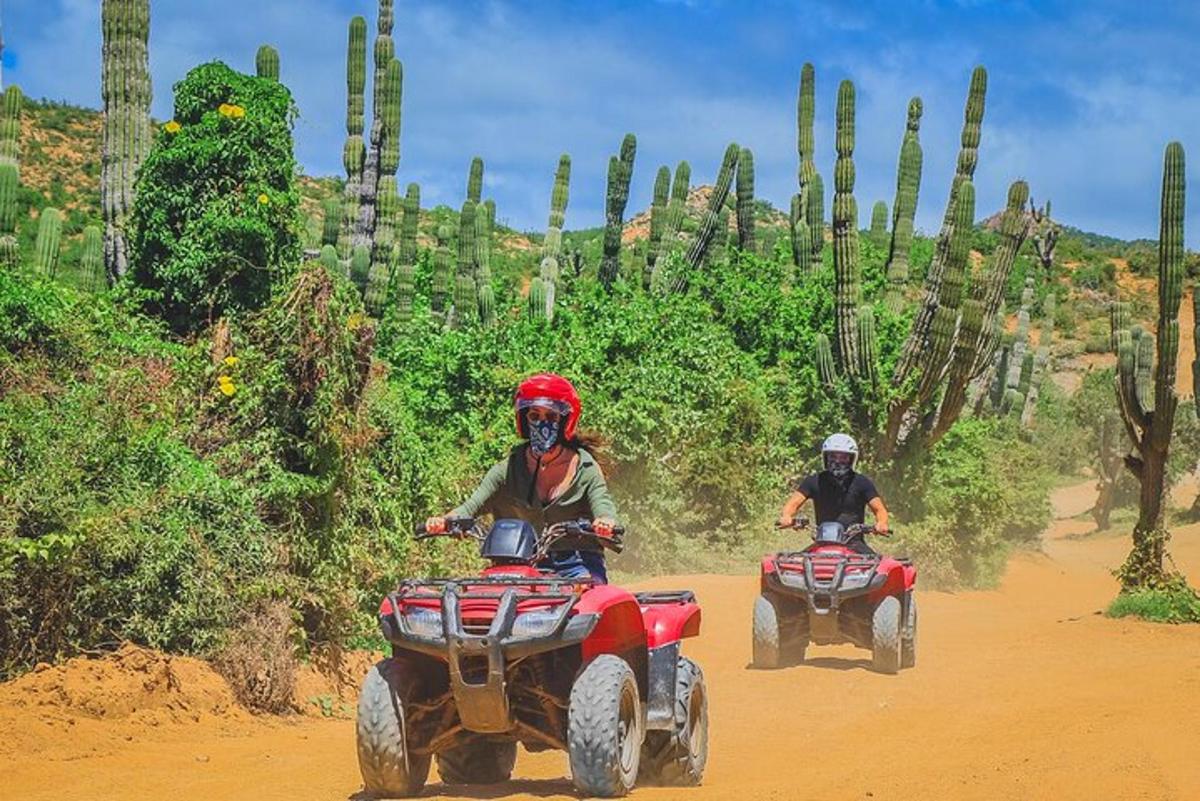 due persone che guidano un quad su una strada sterrata