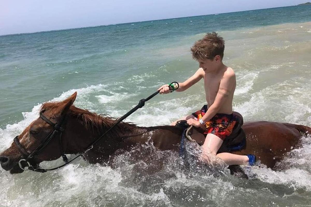 un băiat tânăr călare pe un cal în ocean