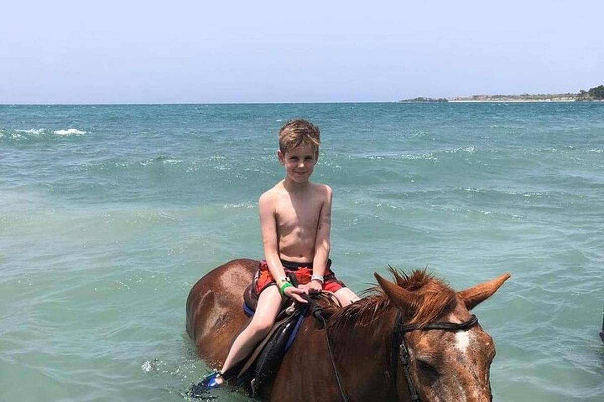 un băiat tânăr stând pe un cal în ocean