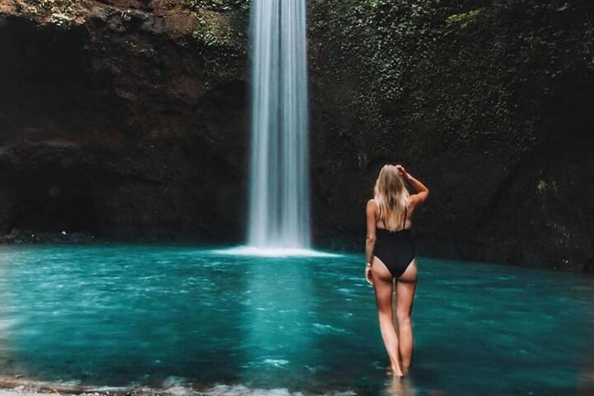 seorang wanita berdiri di dalam air di hadapan air terjun