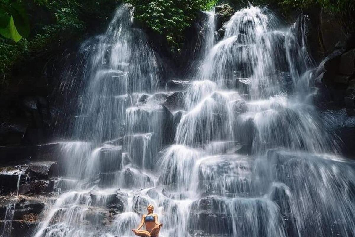 seorang wanita duduk di hadapan air terjun