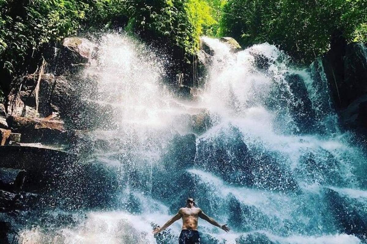 seorang lelaki berdiri di hadapan air terjun