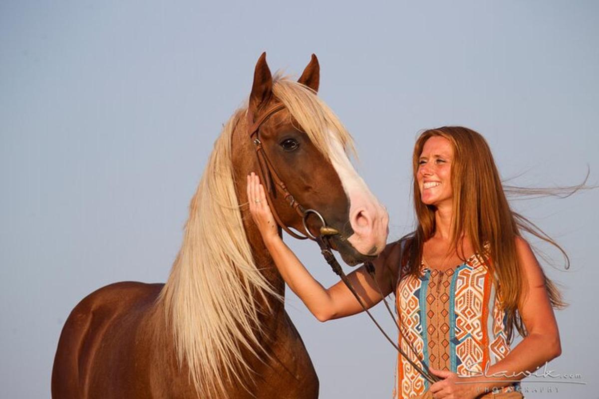 een vrouw die naast een bruin paard staat