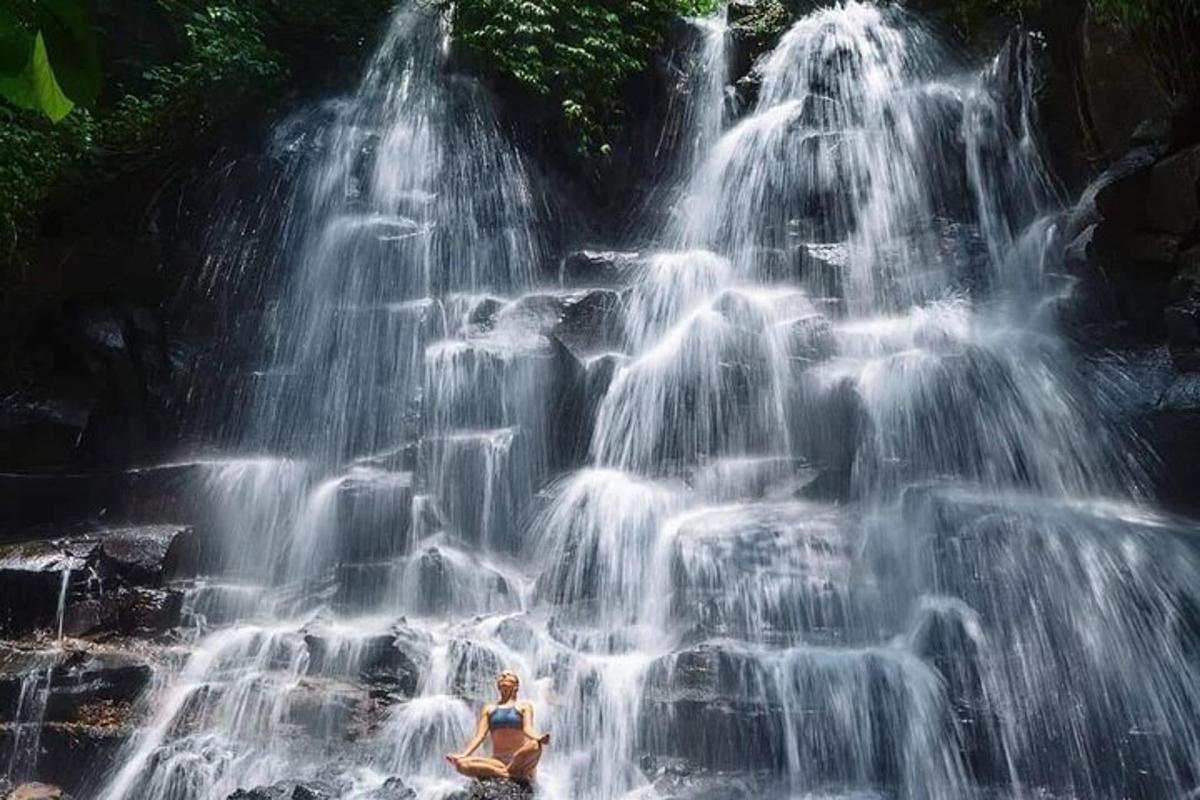 seorang wanita duduk di hadapan air terjun