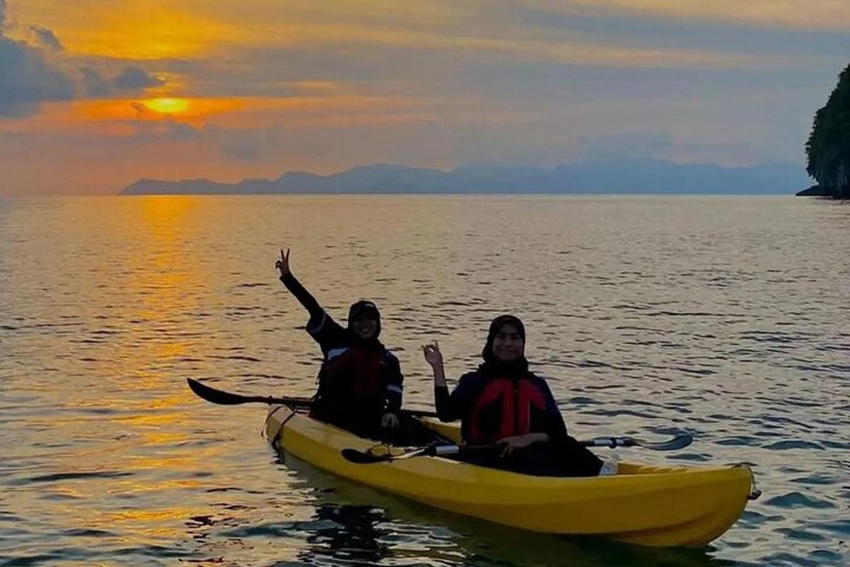 двоје људи у кајаку на води у залазак сунца