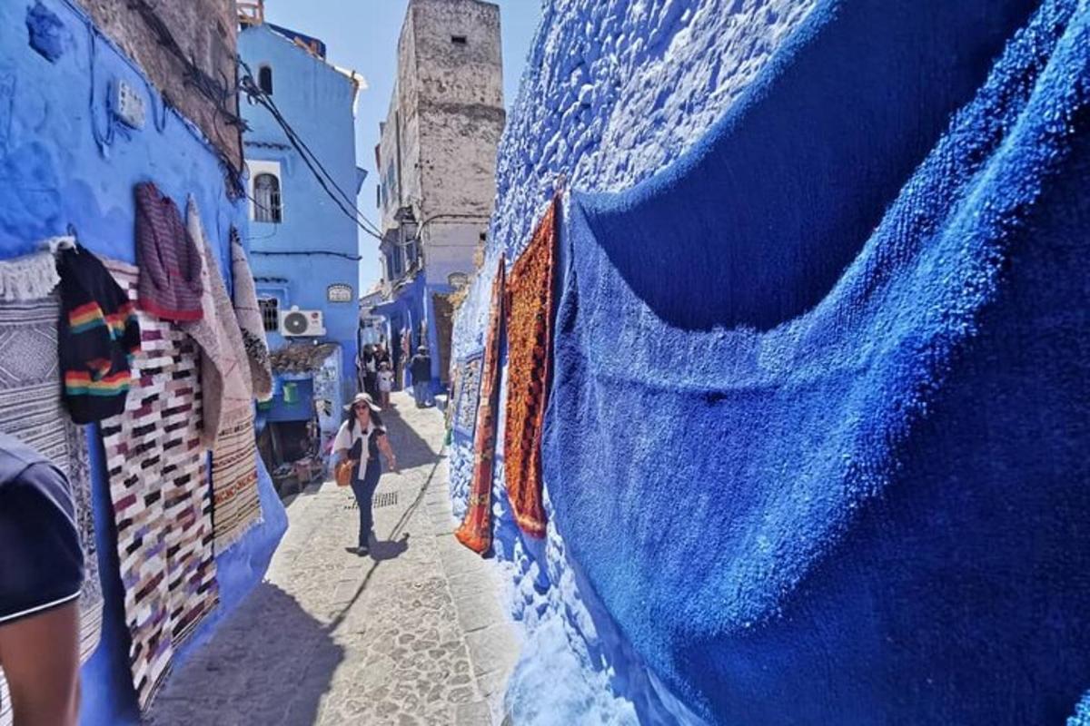 a woman walking down a alley with a blue wall