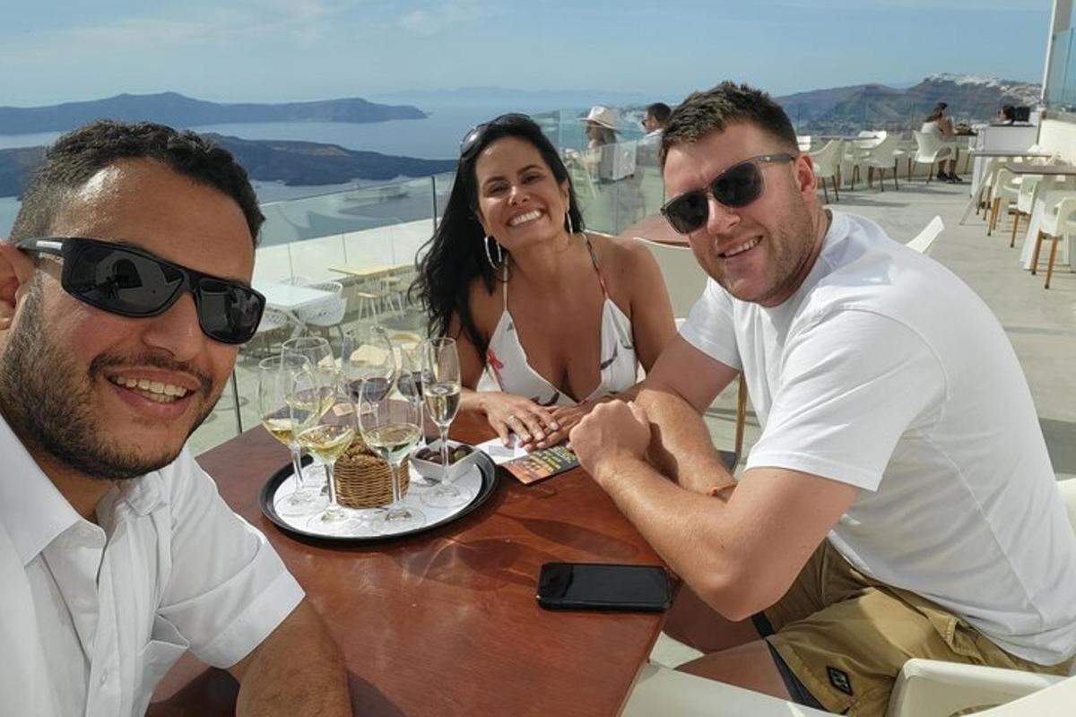 Két férfi és egy nő ül egy asztalnál borospoharakkal