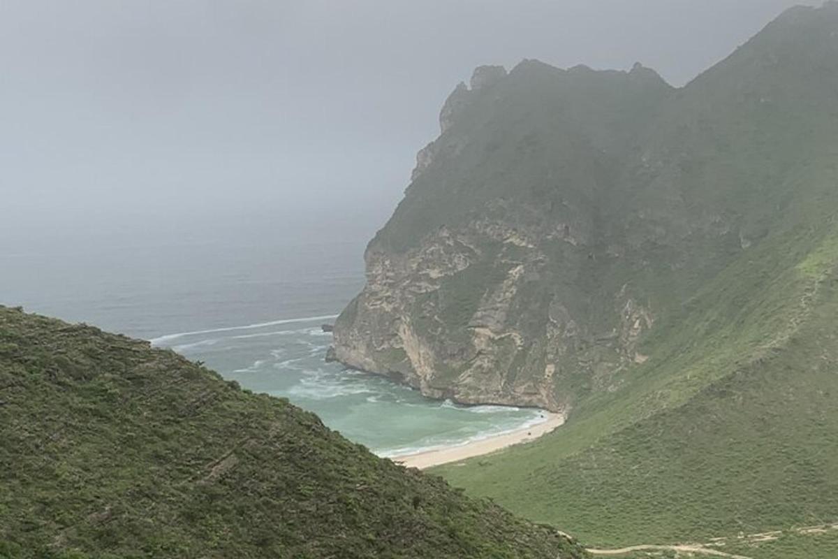 a view of a mountain with a beach and the ocean
