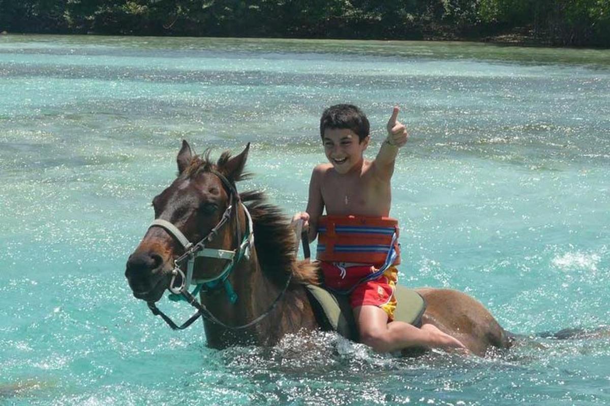 un băiat tânăr călare pe un cal în apă