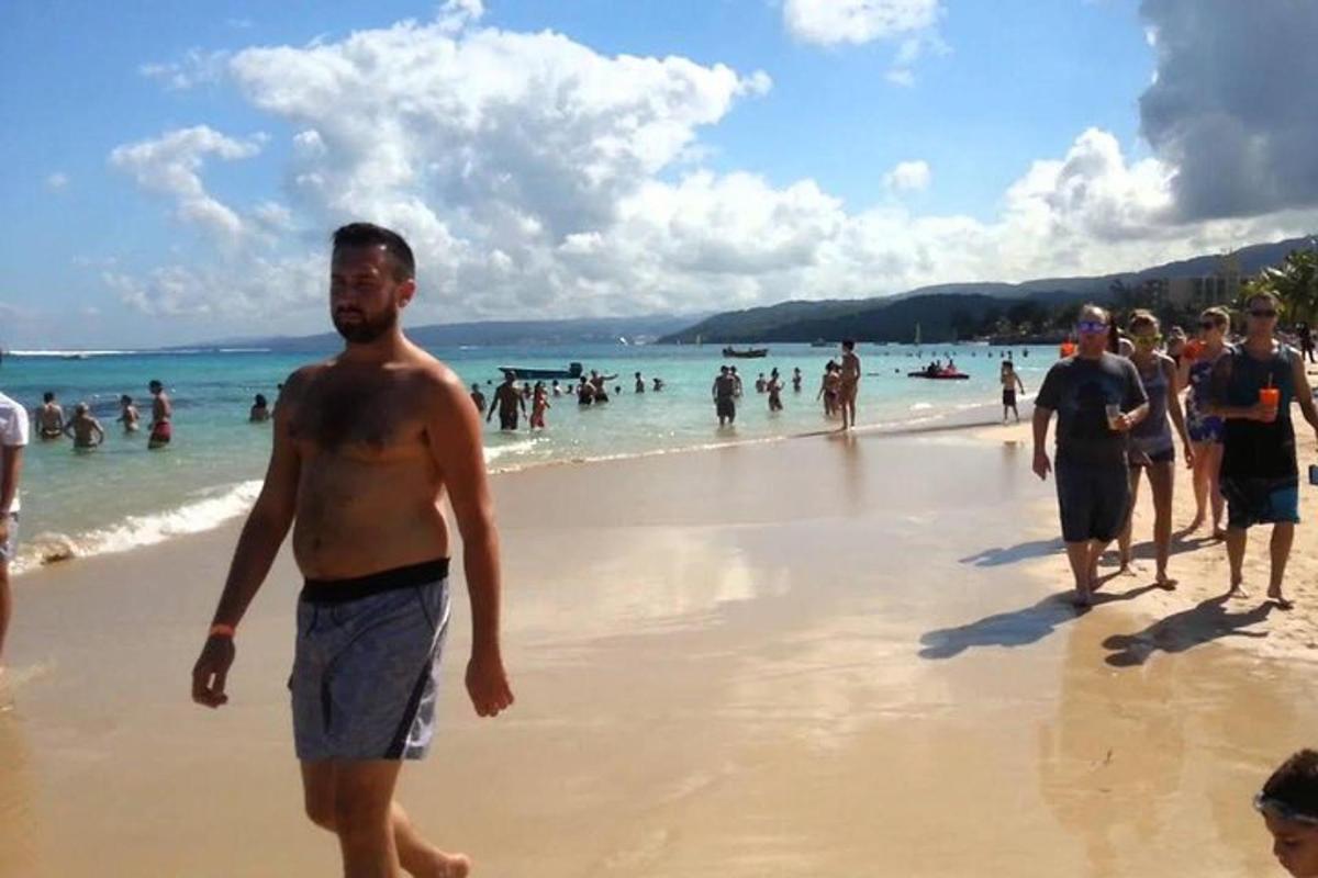 un home caminant per una platja amb un grup de persones